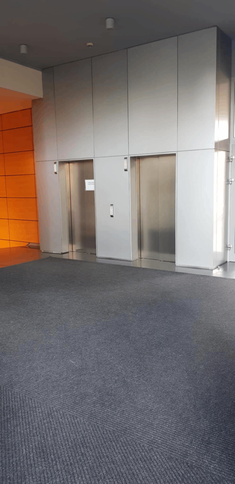 Dwie metalowe windy na tle szarej ściany